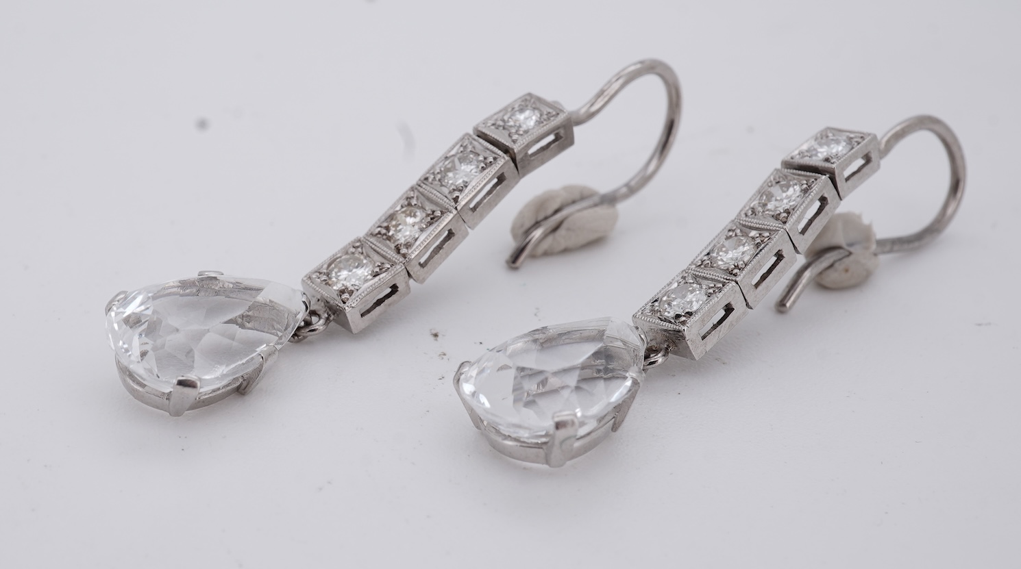 A pair of white metal and four stone diamond set earrings, each with a cubic zirconia pear shaped drop, overall 42mm.